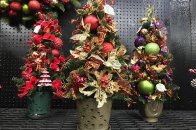 Three small, potted Christmas trees decorated with colorful bulbs and ornaments